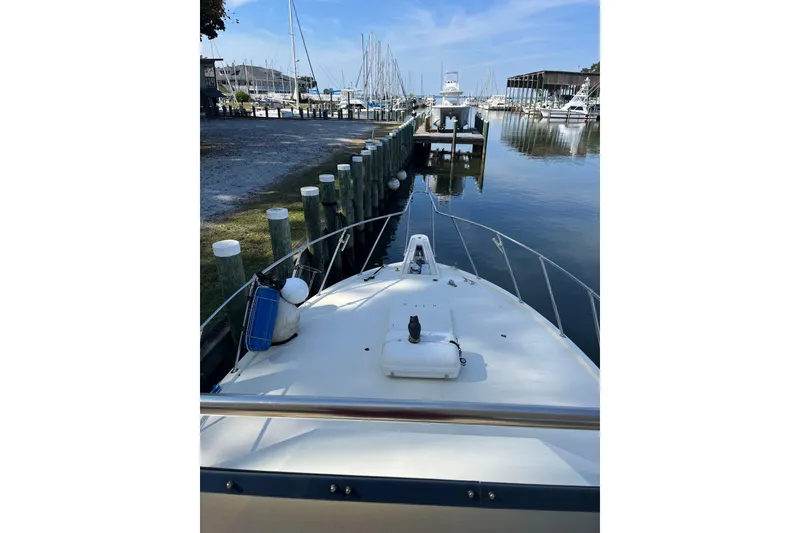 Slide: The Image of 1987 Hatteras 41 Convertible yacht docked at a marina, calm water, clear sky. - 2