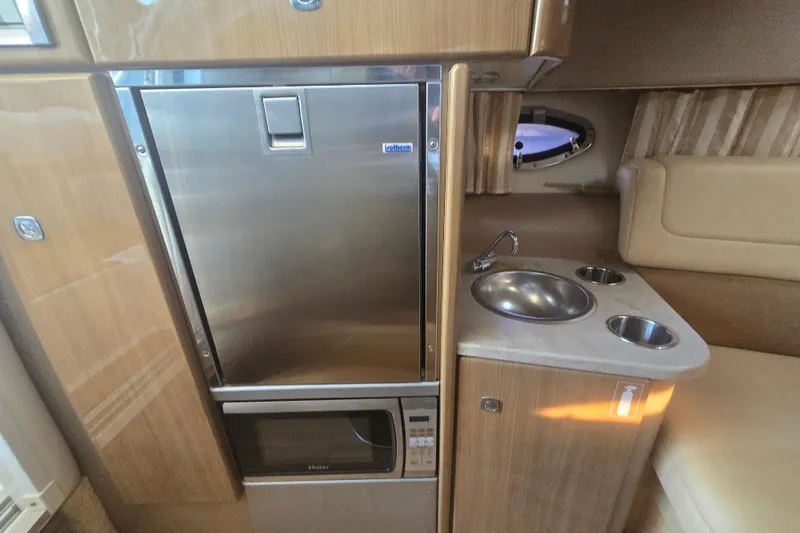 Slide: The Image of 2013 Formula 310 Sun Sport interior with kitchenette, featuring fridge, sink, and microwave. - 23