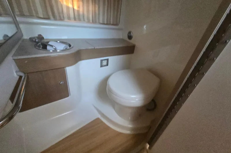 Slide: The Image of 2013 Formula 310 Sun Sport bathroom with sink and toilet, featuring wood accents. - 25