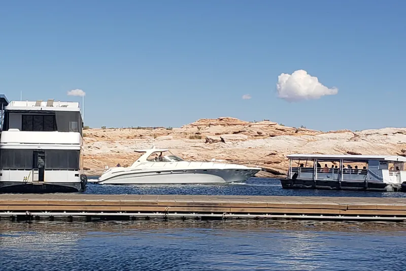 Slide: The Image of Sea Ray Sundancer 540 yacht cruising near rocky shoreline under clear blue sky. - 3