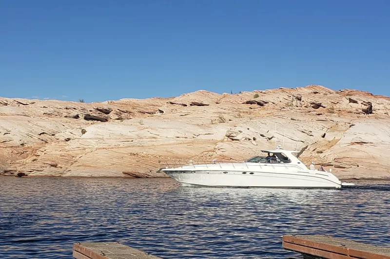 Slide: The Image of 2000 Sea Ray Sundancer 540 yacht cruising on a serene lake with rocky cliffs. - 4