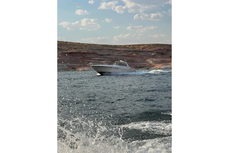 Slide: The Image of Sea Ray Sundancer 540 yacht cruising on a sunny lake with rocky shoreline, 2000 model. - 6