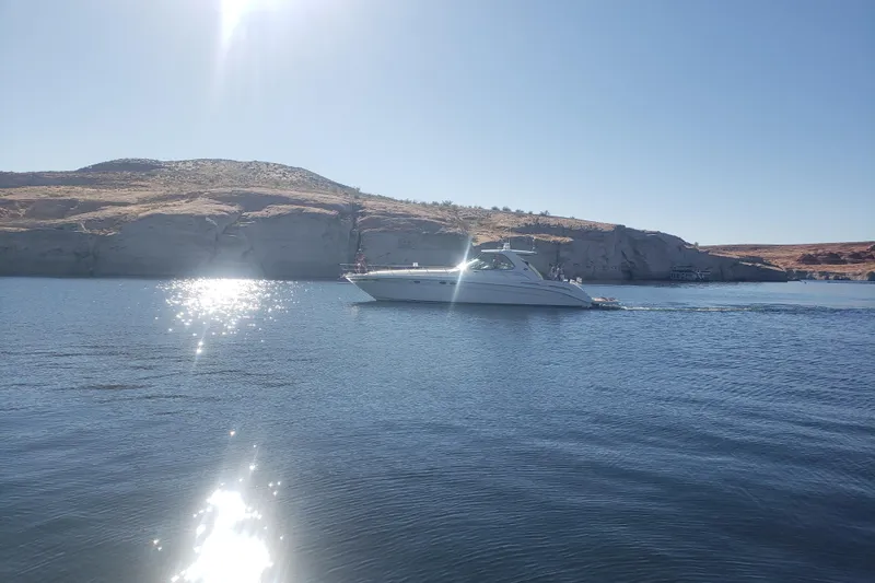 Slide: The Image of Sea Ray Sundancer 540 yacht cruising near rocky cliffs under clear blue sky. - 7
