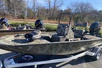 The Image of 2026 G3 Bay 19 GX boat on trailer, camo design, parked outdoors. - 0