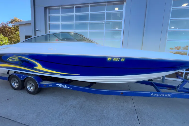 Slide: The Image of 2008 Baja 277 Islander boat on trailer, blue and white design, parked outside garage. - 8