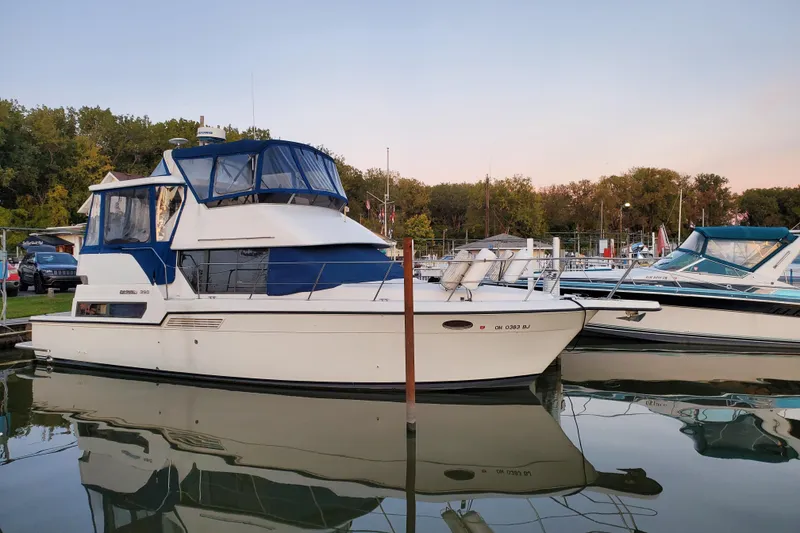 The Image of 1994 Carver 390 Cockpit Motor Yacht docked at sunset, featuring blue canopy and American flag. - 0
