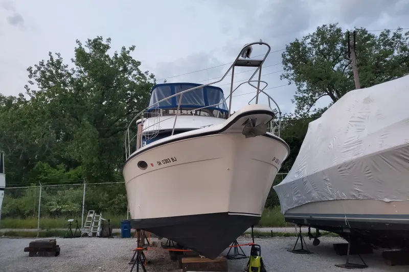 Slide: The Image of 1994 Carver 390 Cockpit Motor Yacht on dry dock, surrounded by trees and covered boats. - 11