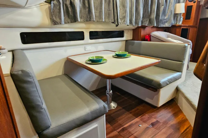 Slide: The Image of 1994 Carver 390 Cockpit Motor Yacht interior dining area with table and cushioned seating. - 25