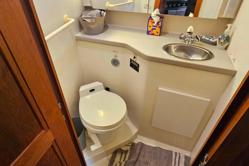 Slide: The Image of 1994 Carver 390 Cockpit Motor Yacht bathroom with toilet, sink, and wooden door. - 28