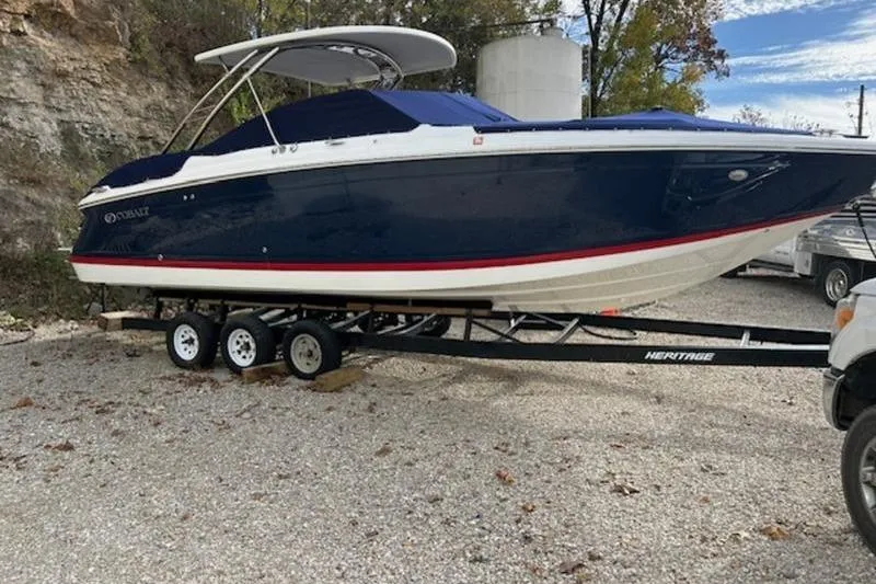 Slide: The Image of 2014 Cobalt 302 boat on trailer, parked outdoors, featuring a sleek blue and white design. - 2