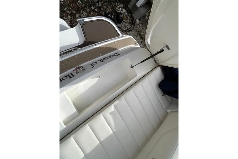 Slide: The Image of 2014 Cobalt 302 boat interior with white seating and open storage compartment. - 9
