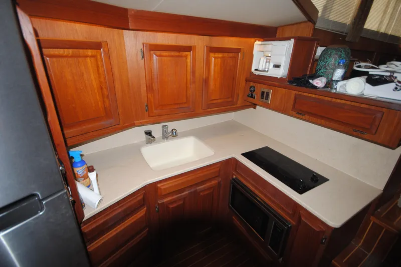 Slide: The Image of 1986 Viking 50 Motor Yacht kitchen with wooden cabinets, sink, and stovetop. - 27