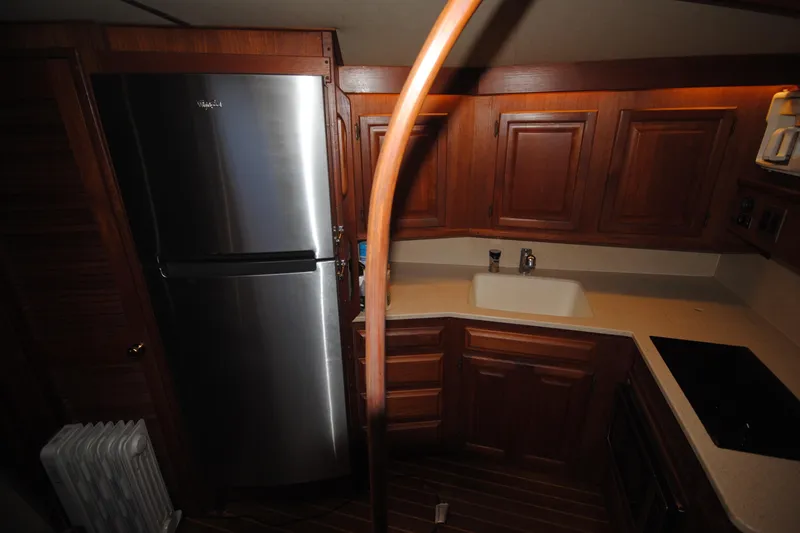 Slide: The Image of 1986 Viking 50 Motor Yacht kitchen with wooden cabinets and stainless steel refrigerator. - 28