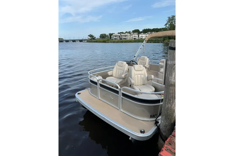 Slide: The Image of 2015 Bennington 175 pontoon boat docked with people onboard, scenic lake view. - 3