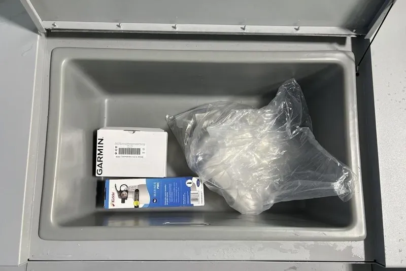 Slide: The Image of Storage compartment of 2026 Tracker Bass Tracker Classic CC with Garmin box and plastic bag. - 12