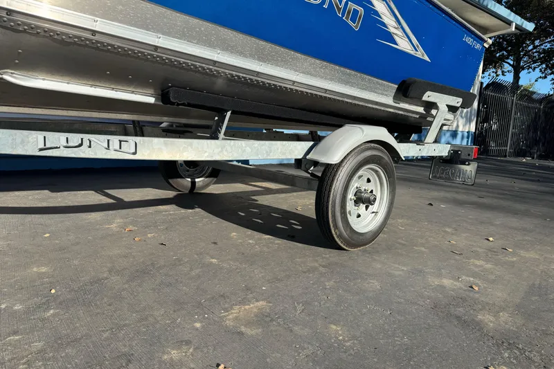 Slide: The Image of 2024 Lund 1400 Fury SS boat on trailer, side view, blue and silver design. - 1