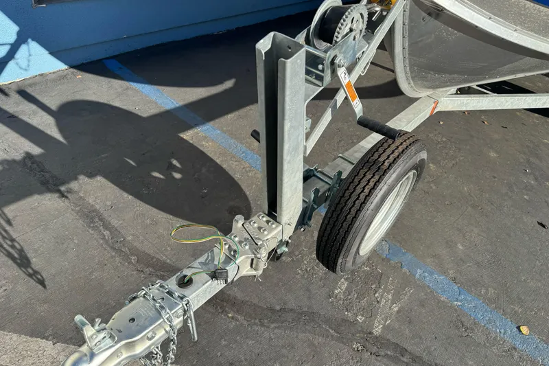 Slide: The Image of Trailer hitch and wheel of 2024 Lund 1400 Fury SS boat on pavement. - 2