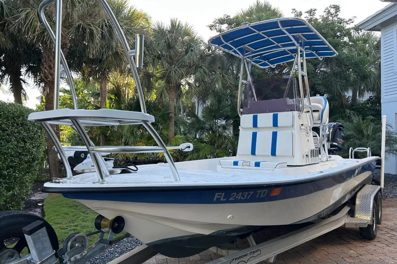 The Image of 2018 Shallow Sport 24 Modified V boat on trailer, surrounded by lush greenery. - 0