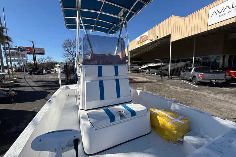 Slide: The Image of 2018 Shallow Sport 24 Modified V boat with blue-striped seating and canopy in a dealership lot. - 45