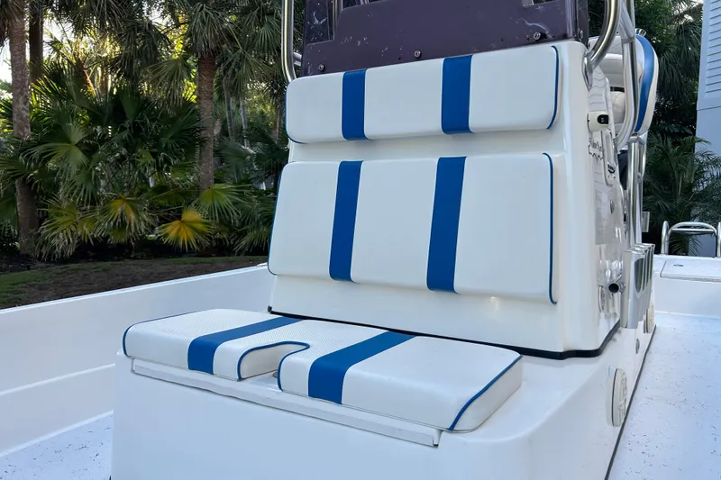 Slide: The Image of 2018 Shallow Sport 24 Modified V boat seating with blue and white cushions, surrounded by lush greenery. - 5