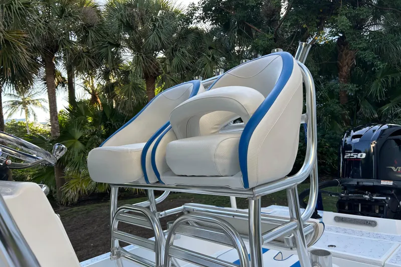 Slide: The Image of 2018 Shallow Sport 24 Modified V boat seats with blue accents, surrounded by lush greenery. - 8