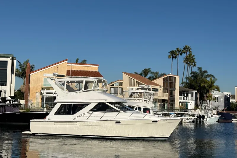 The Image of 1995 Bayliner 39 Motoryacht docked near waterfront homes under clear blue sky. - 0