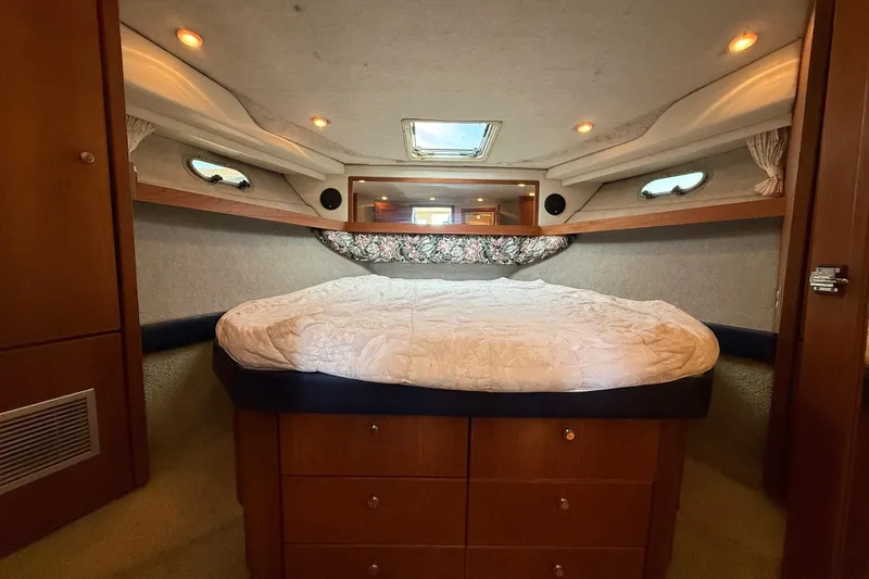 Slide: The Image of 1995 Bayliner 39 Motoryacht bedroom with cozy bed, wooden cabinets, and ambient lighting. - 14