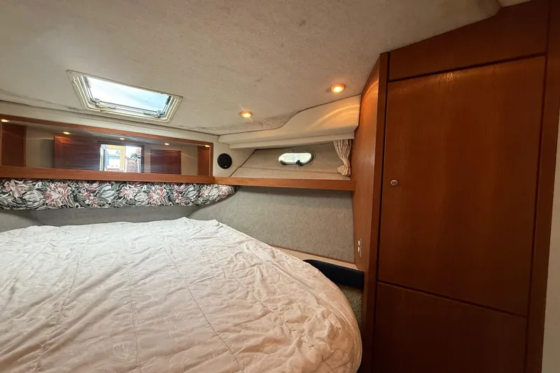 Slide: The Image of 1995 Bayliner 39 Motoryacht cabin interior with bed, wooden cabinetry, and skylight. - 16