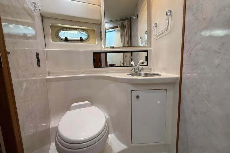Slide: The Image of Bathroom interior of 1995 Bayliner 39 Motoryacht with sink, toilet, and porthole window. - 19