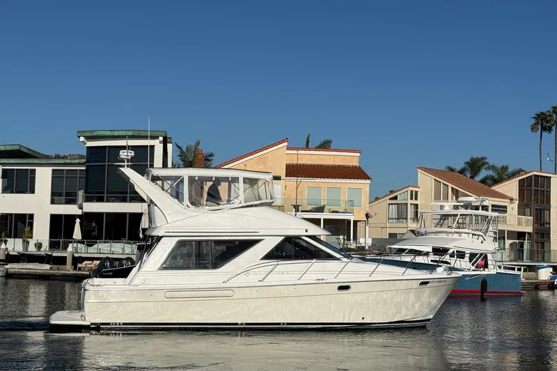 Slide: The Image of 1995 Bayliner 39 Motoryacht docked near waterfront homes under clear blue sky. - 2
