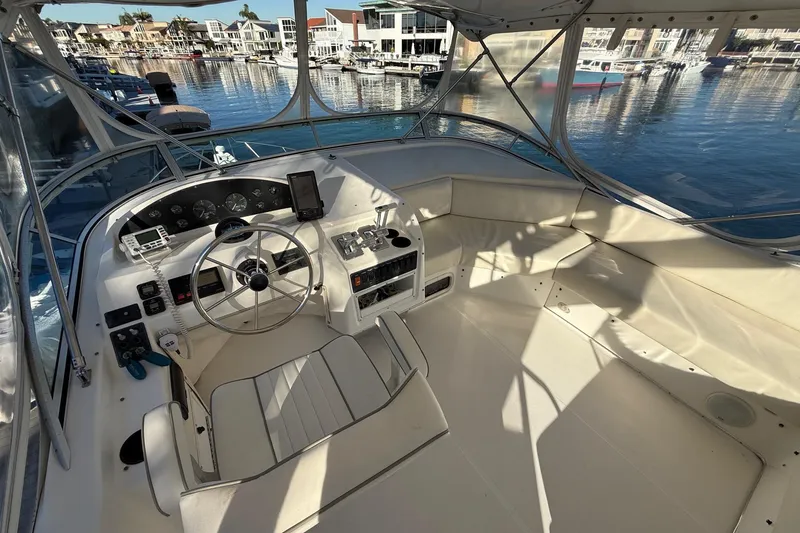 Slide: The Image of 1995 Bayliner 39 Motoryacht helm with steering wheel, controls, and waterfront view. - 20