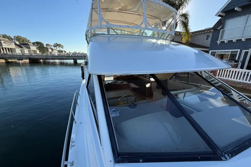 Slide: The Image of 1995 Bayliner 39 Motoryacht docked by waterfront homes, showcasing upper deck and helm. - 27