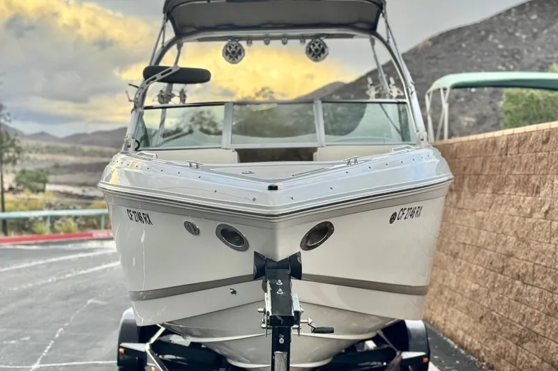 Slide: The Image of 2014 Cobalt 262 WSS boat on trailer, parked outdoors with scenic mountain backdrop. - 2