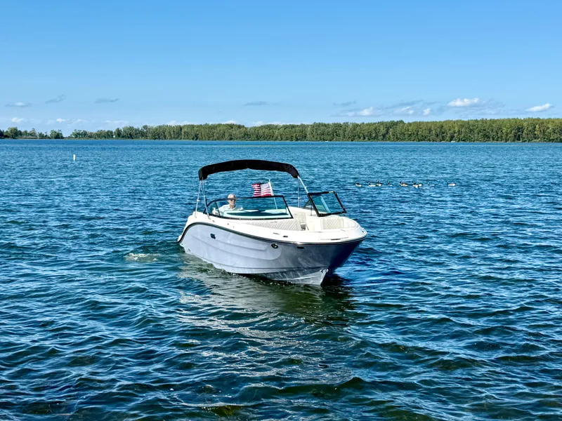 Slide: The Image of 2026 Sea Ray SDX 230 Outboard on a calm lake with a wooded shoreline in the background. - 1