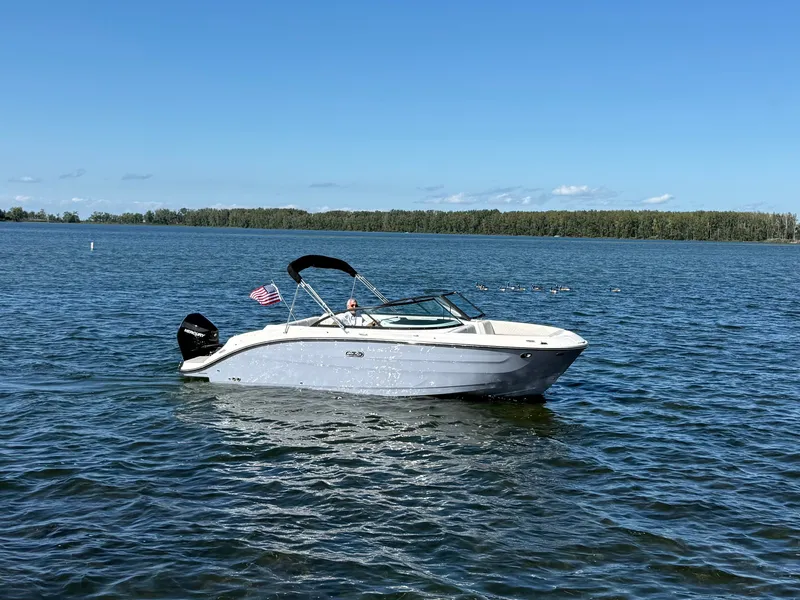 Slide: The Image of A 2026 Sea Ray SDX 230 Outboard on a calm lake with a wooded shoreline. - 19