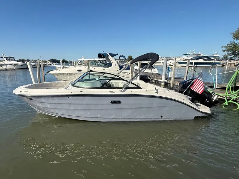 Slide: The Image of A 2026 Sea Ray SDX 230 Outboard docked in the water, featuring a US flag. - 21