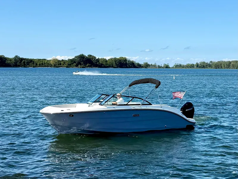 Slide: The Image of A 2026 Sea Ray SDX 230 Outboard on calm waters with a US flag. - 20