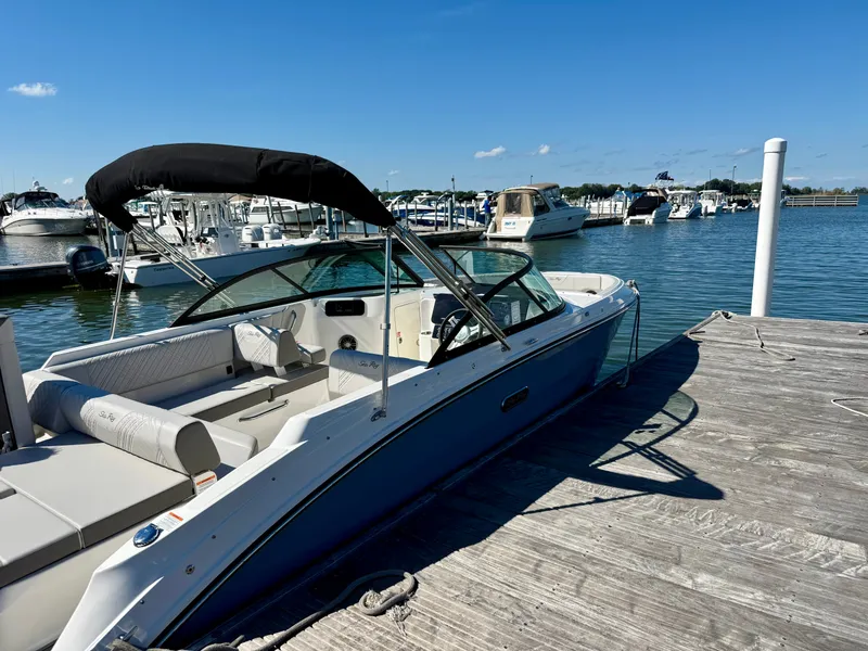 Slide: The Image of Sea Ray SDX 230 Outboard 2026 at dock with blue hull and black bimini top. - 13