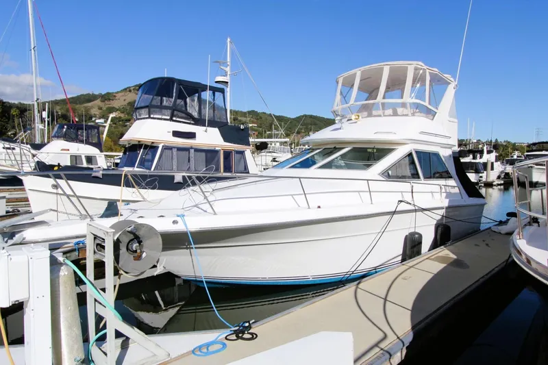 Slide: The Image of 1989 Sea Ray 345 Sedan Bridge yacht docked at a marina under clear blue skies. - 0