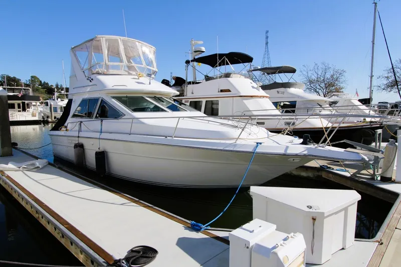 Slide: The Image of 1989 Sea Ray 345 Sedan Bridge yacht docked at marina under clear blue sky. - 1