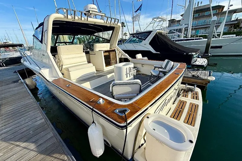 Slide: The Image of 1990 Tiara Yachts 3600 Open docked at marina, showcasing spacious deck and seating. - 14