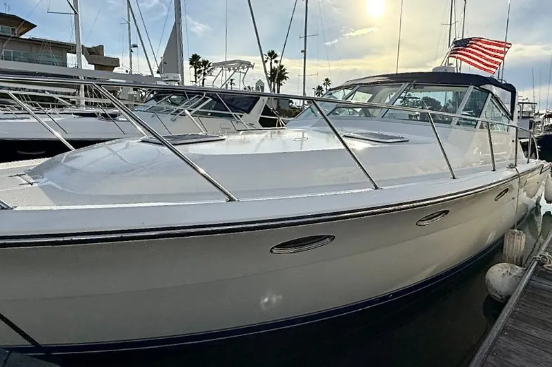 Slide: The Image of 1990 Tiara Yachts 3600 Open docked, featuring sleek design and American flag. - 2