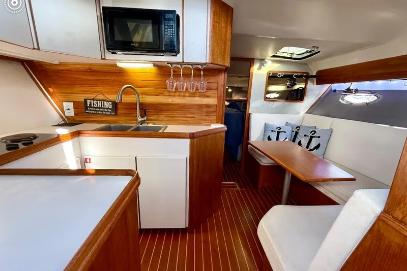 Slide: The Image of 1990 Tiara Yachts 3600 Open interior with kitchen and dining area, featuring wood accents. - 3
