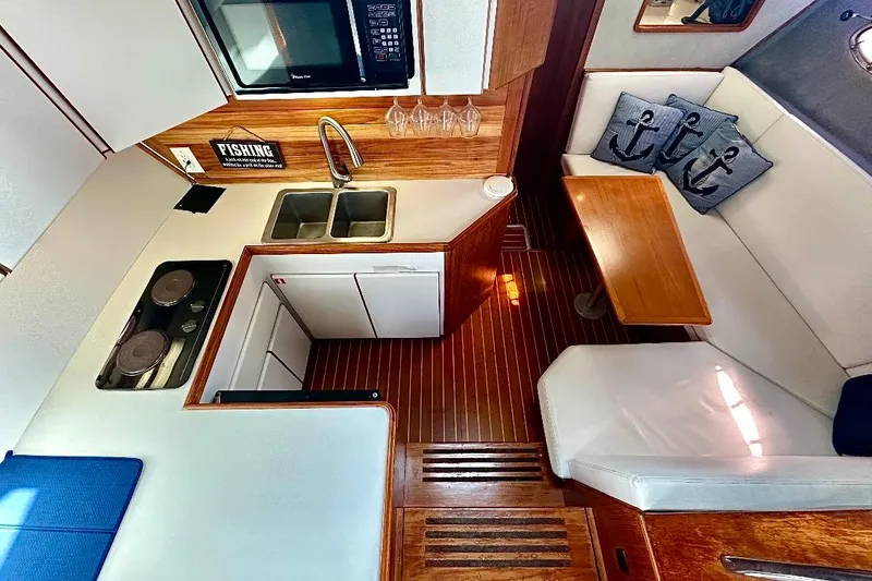 Slide: The Image of 1990 Tiara Yachts 3600 Open interior with kitchen and dining area, featuring wood accents. - 9