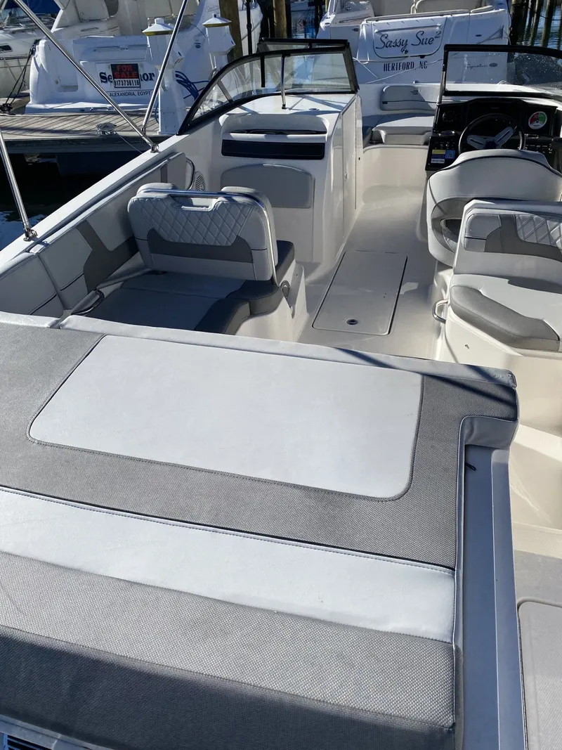 Slide: The Image of 2024 Bayliner VR6 boat interior with seating and dashboard, docked at a marina. - 2