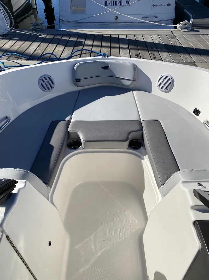 Slide: The Image of 2024 Bayliner VR6 boat interior with cushioned seating and cup holders, docked at a marina. - 3