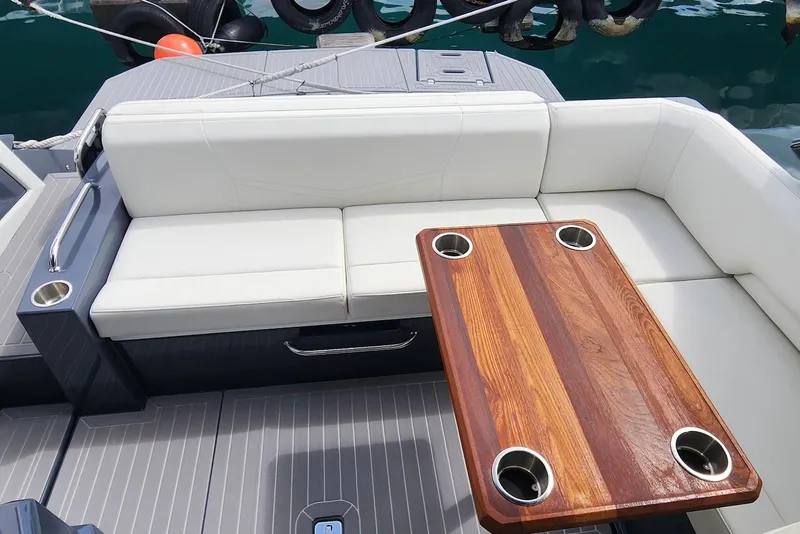 Slide: The Image of 2022 Cruisers Yachts 338 South Beach Edition Bow Rider interior with seating and wooden table. - 19
