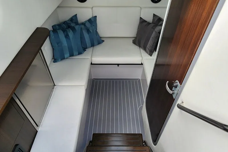 Slide: The Image of 2022 Cruisers Yachts 338 South Beach Edition cabin with white seating and striped pillows. - 26