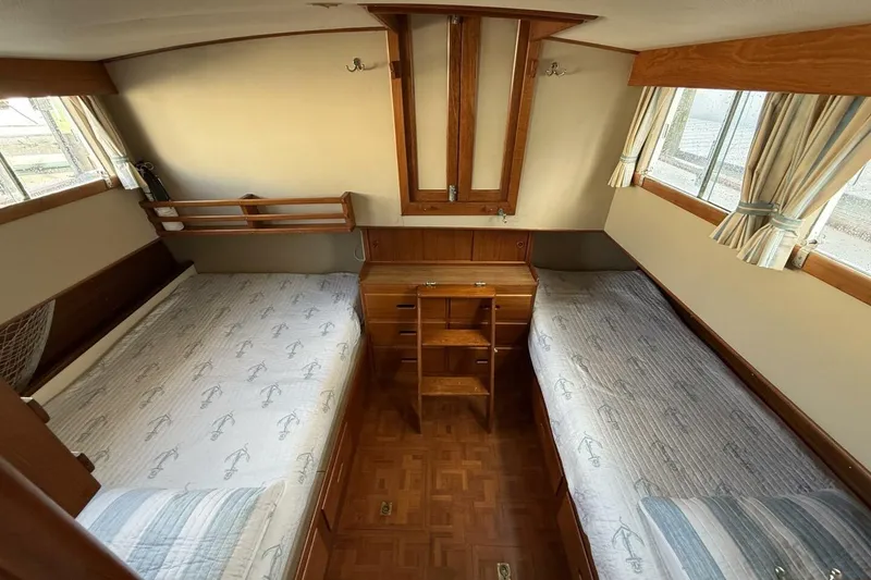 Slide: The Image of 1985 Grand Banks 36 Classic cabin interior with twin beds, wooden furnishings, and natural light. - 14