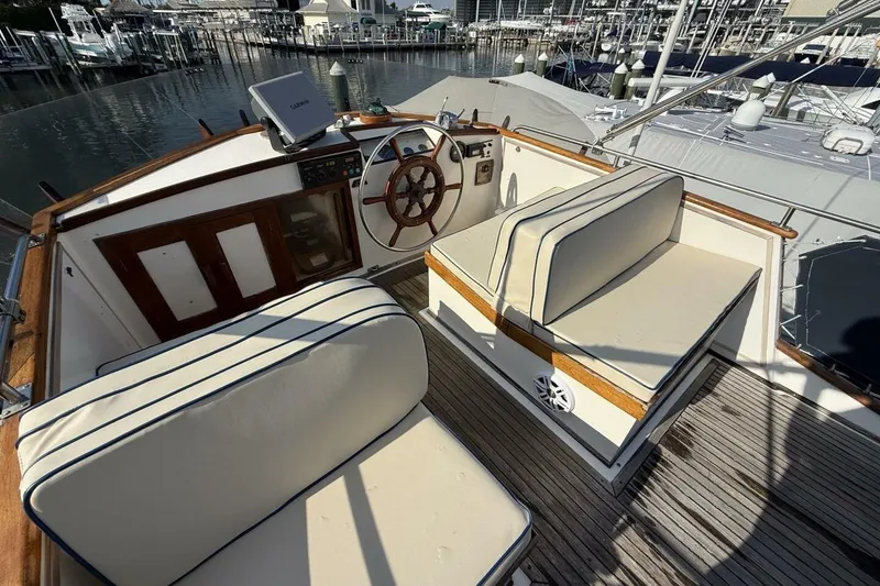 Slide: The Image of 1985 Grand Banks 36 Classic yacht cockpit with wooden helm and cushioned seating. - 6